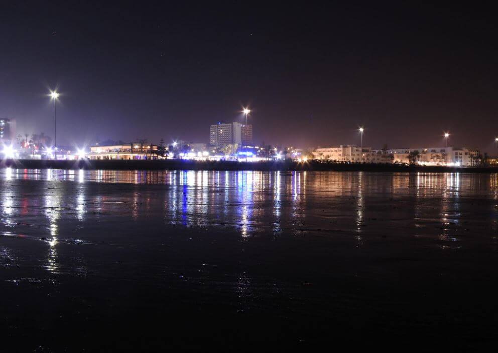 شاطئ أكادير ليلاً مع انعكاس الأضواء على البحر في مدينة Agadir المغرب